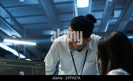 Teamworking colleagues in high tech data center managing and maintaining databases, ensuring data integrity, security and availability. Team of specialists updating server room systems, camera A Stock Photo