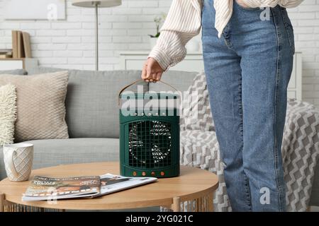 Woman with portable table fan on table at home Stock Photo