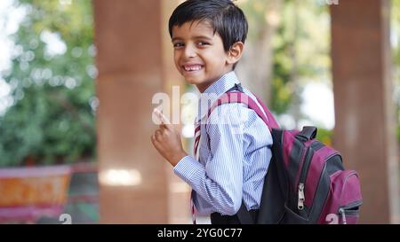 Happy Indian elementary school boy students sitting at desk in classroom with writing in notebook with pencil, Examination and test, male Education co Stock Photo