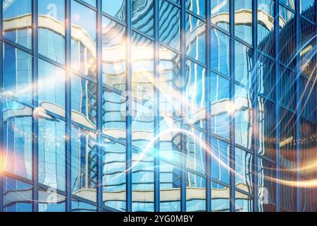 A modern glass building reflects a glowing, abstract pattern of light, creating an illusion of movement. Stock Photo