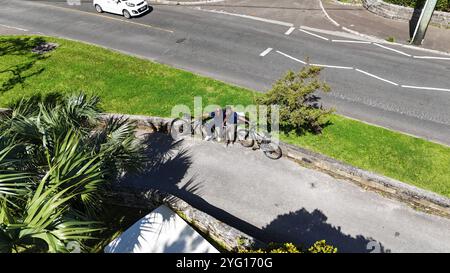 A father and son enjoy a refreshing morning bike ride along the scenic Bermuda coast, cycling beside crystal-clear waters and lush landscapes. Stock Photo