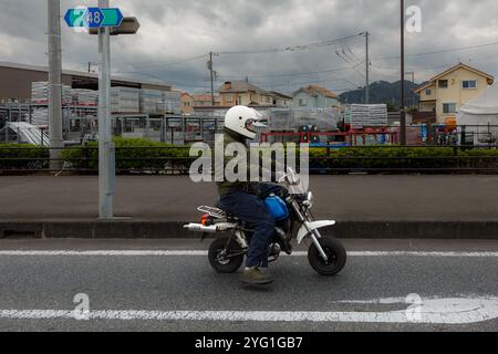 A man rides a tiny Yamaha Pocke motorbike on s road in rural Kanagawa, Japan. Stock Photo