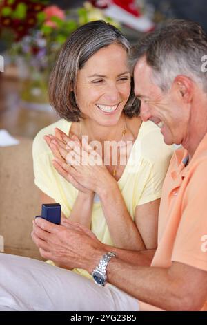 Senior couple, ring and engagement proposal in home for relationship, commitment and romance. Elderly people, happy and jewelry for hand in marriage Stock Photo