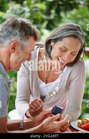 Senior couple, ring and marriage proposal outdoor for relationship, commitment and romance. Elderly people, happy and jewelry for hand in engagement Stock Photo