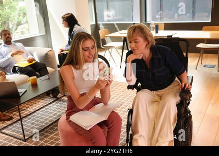 Two businesswomen checking on phone in office Stock Photo