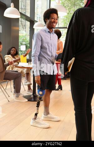 Man with leg prosthesis talking with woman in office Stock Photo