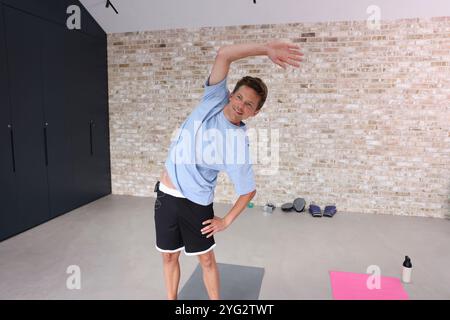 Smiling man stretching in gym Stock Photo