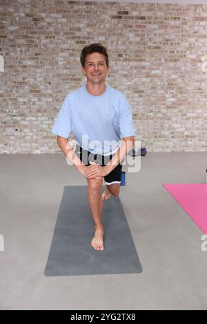 Smiling man doing lunge in gym Stock Photo
