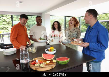 Friends preparing food in kitchen Stock Photo