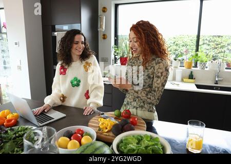 Two women checking on phone and laptop Stock Photo