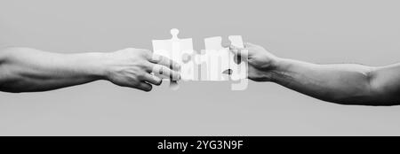 Close up, hands holding trying to connect couple jigsaw puzzle pieces. Men holding and putting a piece of jigsaw puzzle together. Man hands connecting Stock Photo