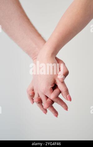 Close up of loving couple holding hands. Intertwined fingers over white background. Stock Photo