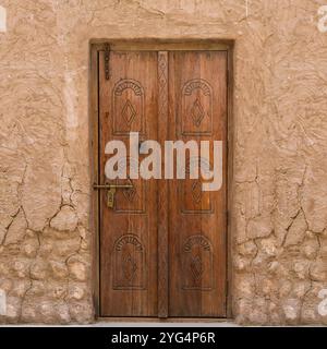Middle eastern vintage traditional wooden front door, weathered with carved orient design details in old city district. Typical arabic exterior style Stock Photo