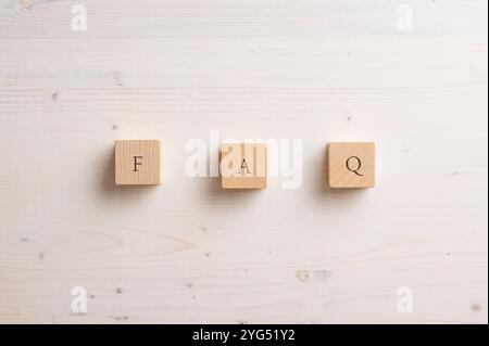Three wooden blocks with the letters "F," "A," and "Q" arranged on a light wood surface, representing the abbreviation for Frequently Asked Questions. Stock Photo