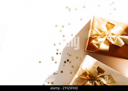 Two Christmas gift boxes, adorned with vibrant golden ribbons on white background with shadows. Flat lay. Copy space Stock Photo