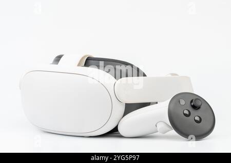 Virtual reality headset paired with controller rests on smooth surface, showcasing sleek, modern technology. Stock Photo