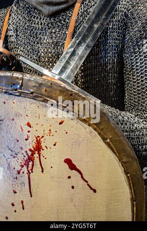 Medieval warrior in iron shirt holding sword and bloody shield Stock Photo