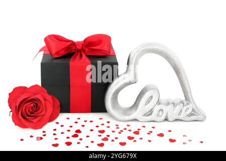 Valentine red rose flower, gift box, scattered hearts and, love sign on white. Romantic concept for a Valentines Day card, anniversary  birthday. Stock Photo