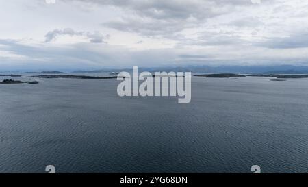 Aerial view of a calm sea with scattered small islands under a cloudy sky. Stock Photo