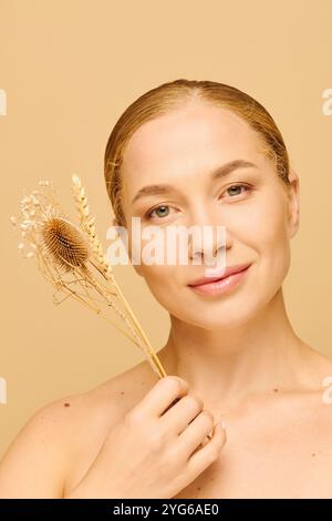 A young plus size woman smiles softly while holding delicate dried flowers. Stock Photo