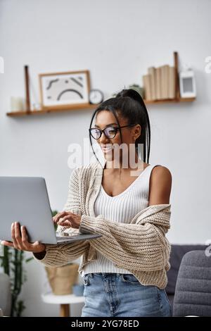 A cheerful woman engages in remote study while seated comfortably at home, feeling inspired. Stock Photo