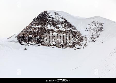 A dramatic winter landscape with a rugged mountain peak stands tall, covered in snow and ice Stock Photo