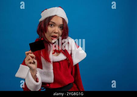 A woman in a red santa outfit holding a black card Stock Photo