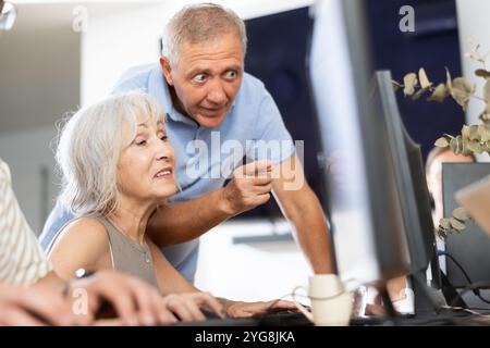 Older mentor explaining something to elderly woman during computer class Stock Photo