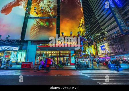 Times Square subway entrance with neon lights, advertisements, and bustling street life at night in New York City. USA. Stock Photo