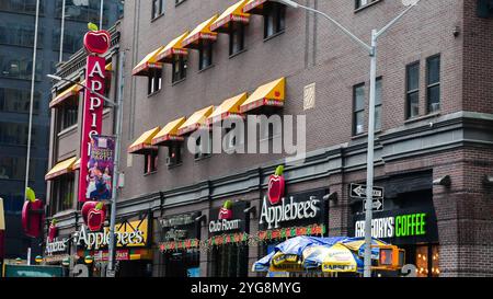 NEW YORK, NY USA - JANUARY 10,  2024: An Applebee's restaurant with yellow awnings and a large red apple logo is visible in the middle of a city street Stock Photo