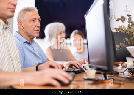 Old man learning computer programs in training room Stock Photo
