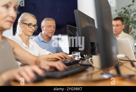Old woman learning computer programs in training room Stock Photo