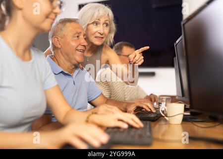 Older female mentor explaining something to elderly man at computer class Stock Photo