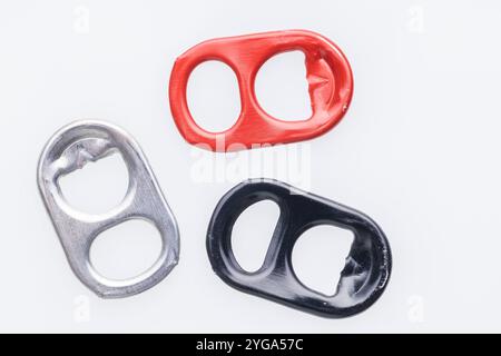 Three can pull tabs, one red, one silver, and one black, are arranged horizontally on a white background. Stock Photo