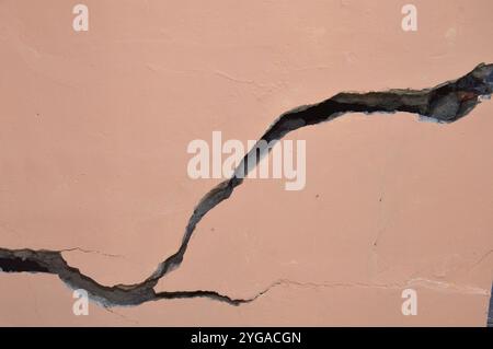cracks in the cement wall are brown, due to earthquake or imperfect construction Stock Photo