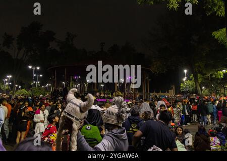 People gathers at night in a Jardín Hidalgo, for a Day of the Dead celebration, featuring festive costumes and lively atmosphere. Día de los Muertos Stock Photo