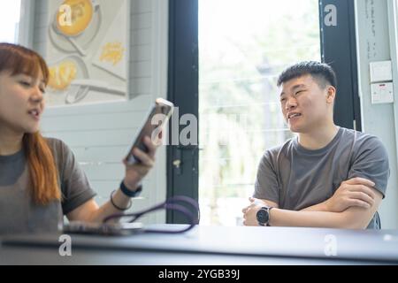 A Chinese Malaysian couple in their 30s spends time at a stylish cafe in Kuala Lumpur, Malaysia. A sunny afternoon in June 2024. Stock Photo