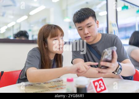 Chinese Malaysian couple in their 30s chatting at a famous local Chinese restaurant in Kuala Lumpur, Malaysia. Stock Photo