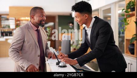 Hotel, happy and man with receptionist in lobby for booking, guest room service and reservation. Hospitality, front desk and person talking with Stock Photo