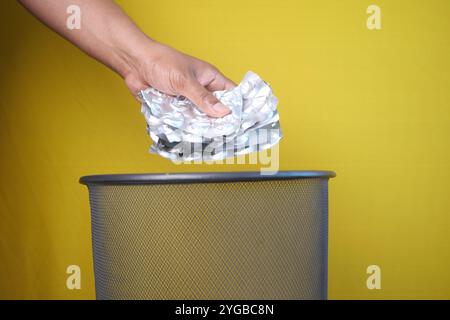 A hand is throwing away expired medicine packet into a trash can. Stock Photo