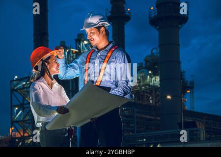 Petroleum refinery industry engineer night time working team. Power plant engineering workers teamwork plant evening survey support. Stock Photo