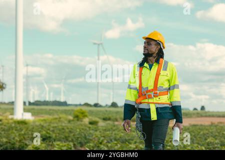 African black engineer technician male worker working service maintenance wind turbine at Wind Turbines electricity generator farm field outdoors. Stock Photo