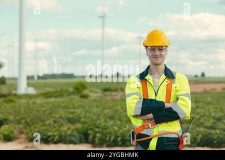 Smart confident Engineer technician male worker standing at Wind Turbines working service at wind electricity generator farm field outdoor. Stock Photo