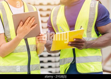 Man and women team workers in reflection safety suit working together join discussion in construction site Stock Photo