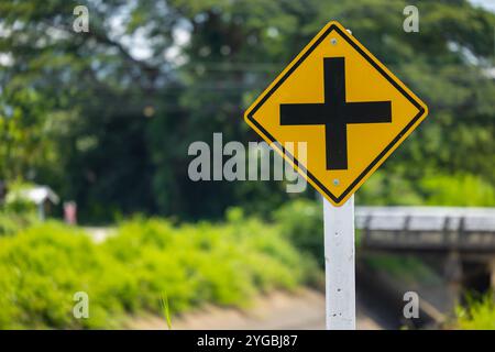 Intersection yellow traffic sign, Four cross road ahead warning, Road sign badge beware of an intersection slow speed car. Stock Photo