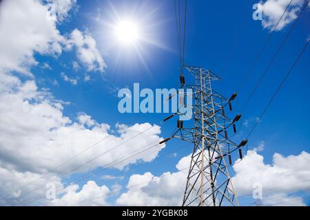 High voltage electric transmission tower, power transmit supply from power plant to the city by electricity pylon on summer cloud sky. Stock Photo