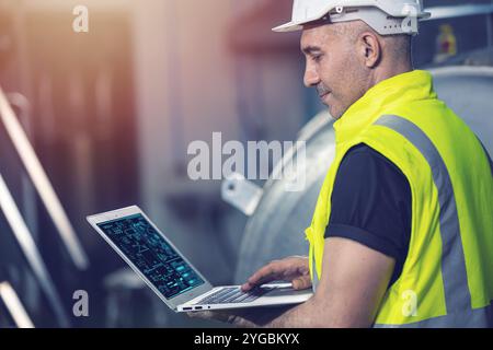 Smart Engineer using laptop computer software program application to help support work service machine on site factory. Stock Photo