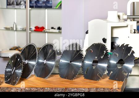 Various circular saw blades displayed on a wooden table in a workshop setting for tools enthusiasts Stock Photo