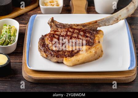 Grilled veal chop on white porcelain plate on wooden table Stock Photo