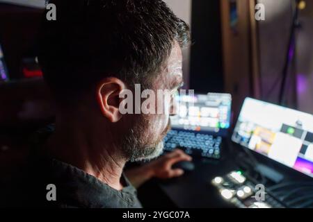 Cybersecurity Professional Analyzing Data on Multiple Screens in a Low-Light Workspace for Network Security Assessment Stock Photo
